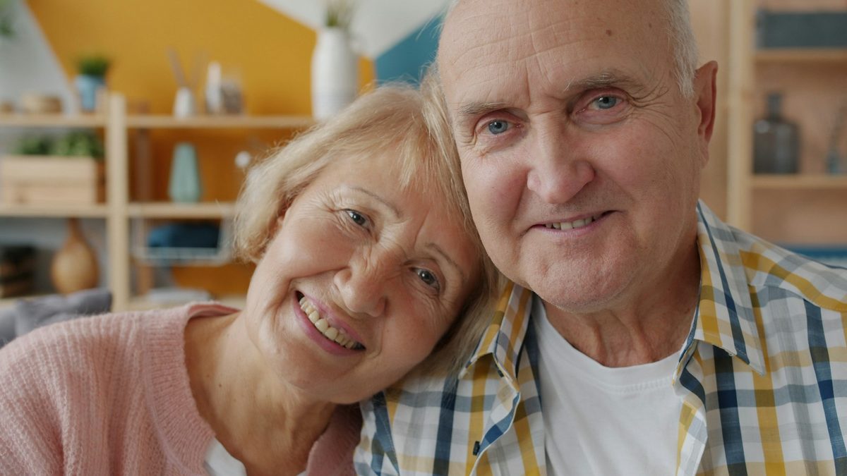 Smiling older couple sitting close together at home